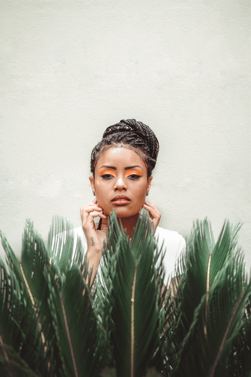 black woman standing near green plant